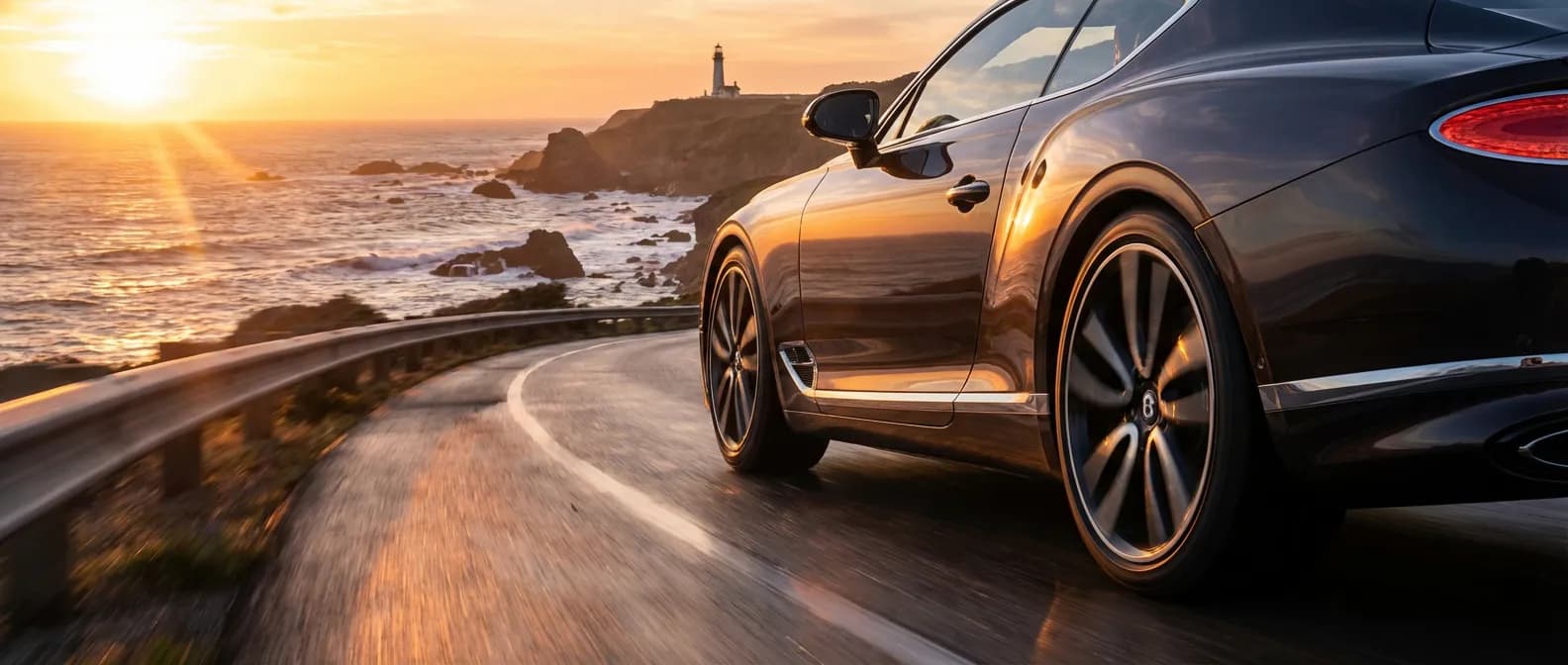 Voiture de luxe sur une route côtière au coucher du soleil mettant en avant la qualité des pneus