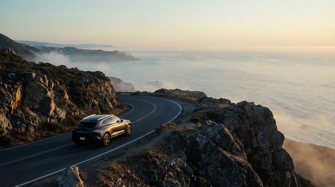 Une voiture de luxe parcourant une route côtière au lever du soleil, symbolisant la liberté et la sérénité du voyage.